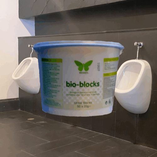 Tub of Bio Blocks in front of a row of urinals