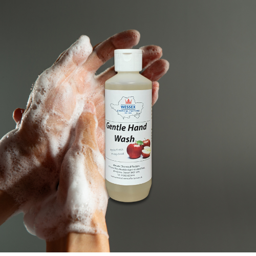 small bottle of gentle hand wash in front of person washing their hands